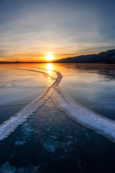 Large cracks in the clear smooth blue ice of Lake Baikal at sunset. Siberia Russia — Stock Photo, Image