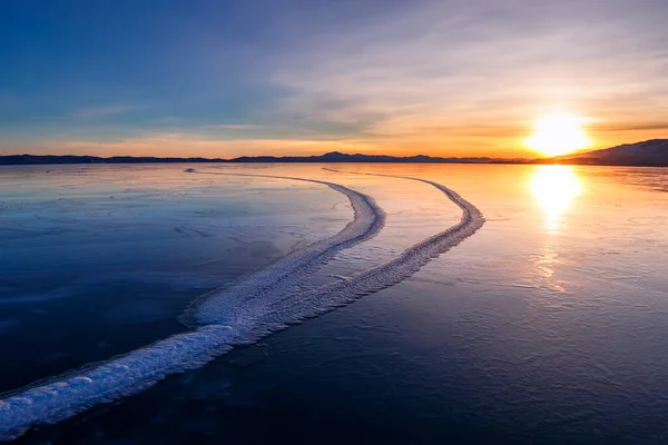 Grandes rachaduras no gelo azul liso claro do Lago Baikal ao pôr do sol. Sibéria Rússia — Fotografia de Stock