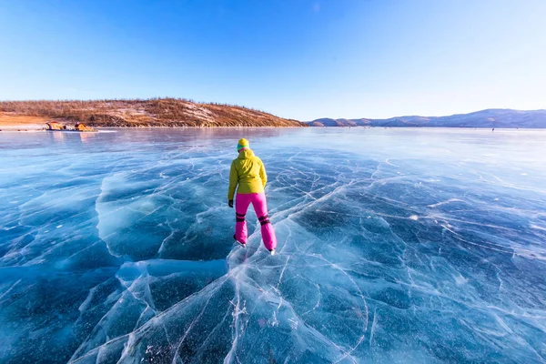 Piedi primi piani di pattini sulle gambe Una donna vestita di colori vivaci sul ghiaccio blu del lago Baikal Foto Stock