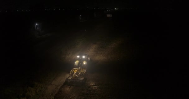 Tractor plowing field at the night aerial view — Stock Video