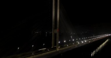 Şehir trafiği modern köprüde, gece hava manzarasında.