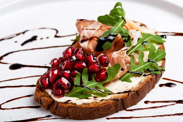 Sandwich with jamon and herbs and pomegranate on white plate macro 免版税图库照片