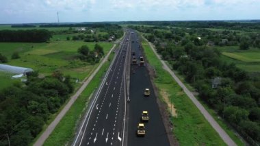Road rollers building the new asphalt road at the summer cloudy aerial view
