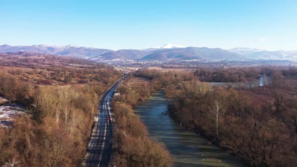 Slingrande väg genom nationalparken omgiven av berg och en rasande flod antenn utsikt — Stockvideo