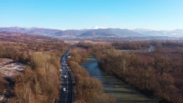 Slingrande väg genom nationalparken omgiven av berg och en rasande flod antenn utsikt — Stockvideo
