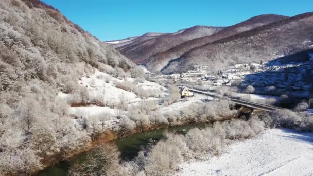 Górska zimowa droga, która przecina rzekę z lotu ptaka — Wideo stockowe