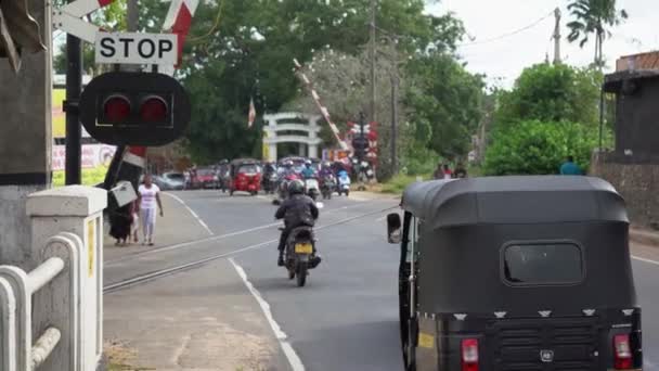 Hikkaduwa, Sri Lanka, January 2022: Drivers go through a railroad crossing after the barrier went up. — Vídeos de Stock