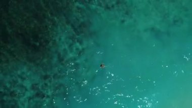 Bikinili kadın plaj havası manzarasında şeffaf turkuaz su yüzeyinde yatıyor..