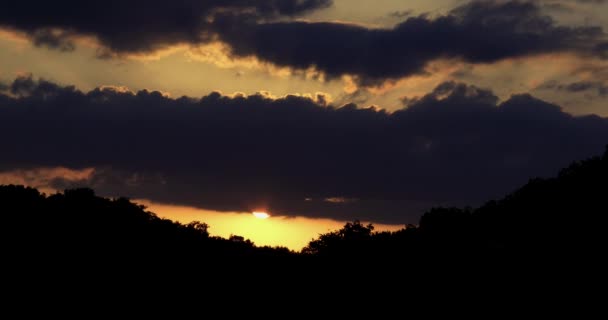 Beautiful sunset time lapse as the sun shines between the clouds and the forest — Stock Video