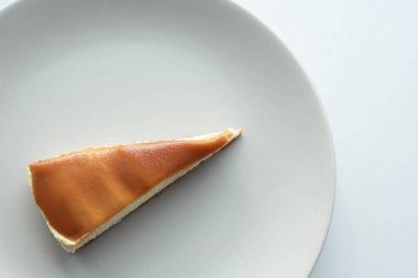 Üstünde tuzlu karamel olan bir dilim peynirli kek.