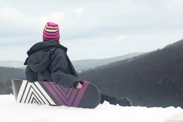 Snowboarding girl enjoying the beautiful view in the mountains