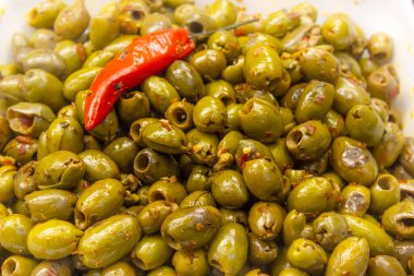 Yeşil zeytinli salata arkaplanı ve üstünde kırmızı biber.