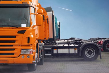 Turuncu kamyon güzel park etmiş, ön manzarası ve fotokopi alanı var.