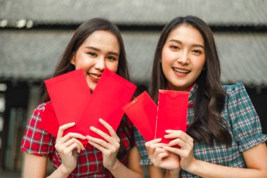 Güzel bir Asyalı kadın Çin Yeni Yılı 'nda geleneksel kırmızı bir cheongsam giyer. Elinde kırmızı bir zarf olan el ya da Çin karakterli Ang Pao mutluluk ya da iyi şans demektir..