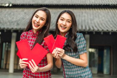 Güzel bir Asyalı kadın Çin Yeni Yılı 'nda geleneksel kırmızı bir cheongsam giyer. Elinde kırmızı bir zarf olan el ya da Çin karakterli Ang Pao mutluluk ya da iyi şans demektir..