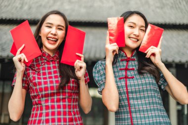 Güzel bir Asyalı kadın Çin Yeni Yılı 'nda geleneksel kırmızı bir cheongsam giyer. Elinde kırmızı bir zarf olan el ya da Çin karakterli Ang Pao mutluluk ya da iyi şans demektir..