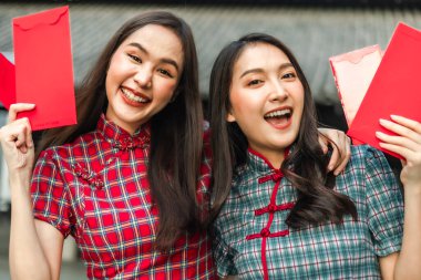 Güzel bir Asyalı kadın Çin Yeni Yılı 'nda geleneksel kırmızı bir cheongsam giyer. Elinde kırmızı bir zarf olan el ya da Çin karakterli Ang Pao mutluluk ya da iyi şans demektir..