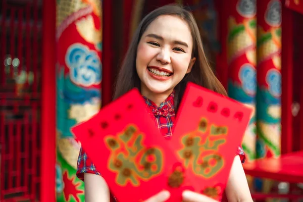 Güzel bir Asyalı kadın Çin Yeni Yılı 'nda geleneksel kırmızı bir cheongsam giyer. Elinde kırmızı bir zarf olan el ya da Çin karakterli Ang Pao mutluluk ya da iyi şans demektir..