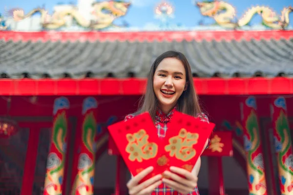 Güzel bir Asyalı kadın Çin Yeni Yılı 'nda geleneksel kırmızı bir cheongsam giyer. Elinde kırmızı bir zarf olan el ya da Çin karakterli Ang Pao mutluluk ya da iyi şans demektir..
