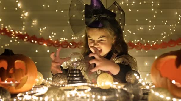 Kleine Hexe zaubert und zaubert. Vor dem Hintergrund der mystischen Attribute von Halloween. Kinder lieben Halloween. — Stockvideo
