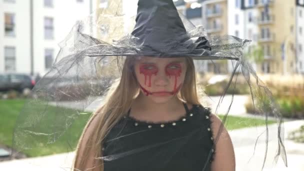 Πορτρέτο μιας έφηβης κοπέλας ντυμένη μάγισσα με τρομακτικό μακιγιάζ στο πρόσωπό της. Απόκριες. — Αρχείο Βίντεο
