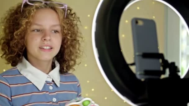 Девушка-блогер делает видеообзор антистрессовых игрушек дома. — стоковое видео