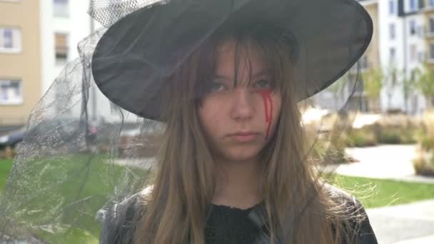 Egy boszorkánynak öltözött tinilány arcképe ijesztő sminkkel az arcán. Halloweeni. — Stock videók