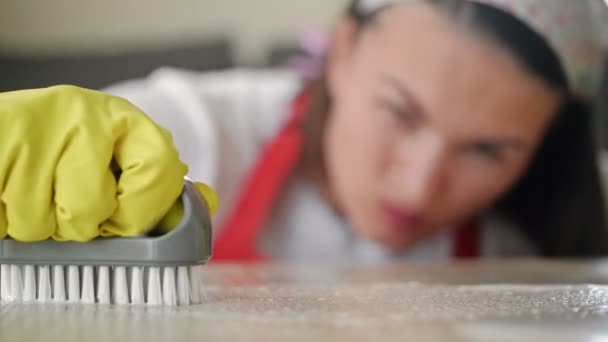 Vrouwen handen in geel rubber handschoenen met moeite schrobben een vlek. — Stockvideo