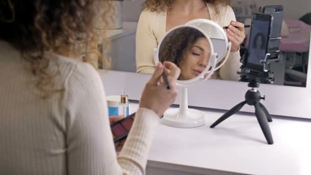 Goed verzorgde, middelbare leeftijd beauty blogger praat over make-up technieken. Een vrouw zit voor een spiegel en een videocamera. — Stockvideo