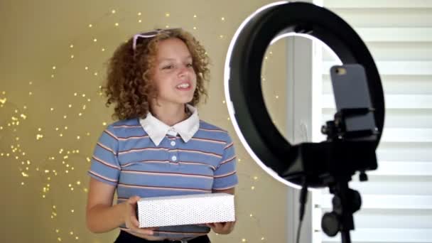 Tonåring bloggare öppnar en låda och spelar in en video för sin blogg. Kommunikation av en video bloggare flicka på sociala nätverk med abonnenter och vänner. — Stockvideo