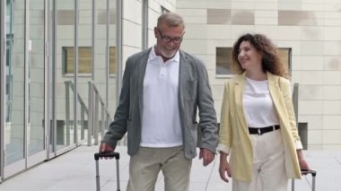 Havaalanında ya da tren istasyonunda yürüyen bavullu bir çift..