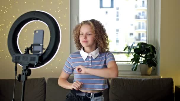Allegra ragazza adolescente che balla alla alla telecamera filmando video utilizzando il telefono su treppiede a casa, creando il suo contenuto alla moda su un'app mobile da condividere sui social media. — Video Stock
