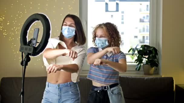 Mladá matka a dospělé dítě v ochranných maskách tančí před kamerou a natáčejí video. Užijte si výhody karantény a vlastní izolace od kovid-19 koronaviru. — Stock video