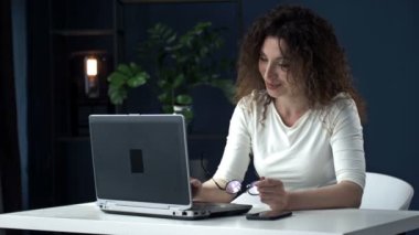 Coronavirus sırasında uzaktan çalışan biri. Ofisteki genç bayan. Görüntülü arama sırasında gülümseyen iş kadını dizüstü bilgisayar kullanıyor.