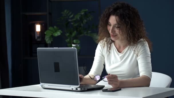 Praca zdalna podczas koronawirusu. Młoda kobieta na stanowisku. Uśmiechnięta kobieta biznesowa korzystająca z laptopa podczas rozmowy wideo. — Wideo stockowe