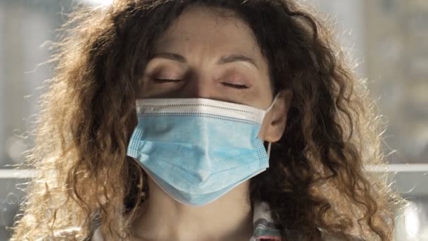 Femme malade avec un masque médical sur le visage avec des symptômes de la grippe, ou le coronavirus se trouve dans le lit. Elle s'inquiète d'une toux sévère, d'un essoufflement et de maux de tête.. — Video
