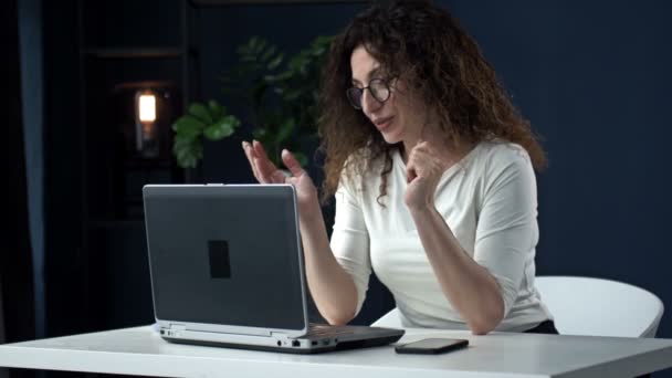 Praca zdalna podczas koronawirusu. Młoda kobieta na stanowisku. Uśmiechnięta kobieta biznesowa korzystająca z laptopa podczas rozmowy wideo. — Wideo stockowe