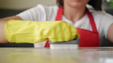 Kadın elleri sarı lastik eldivenlerle leke silmeye çalışıyor..