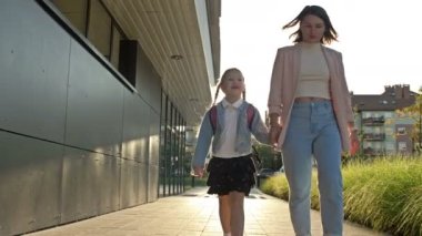 Anne okuldan sonra küçük kızıyla tanışır. Genç bir kadın at kuyruklu bir kızın elini tutuyor. Keyfin yerinde..