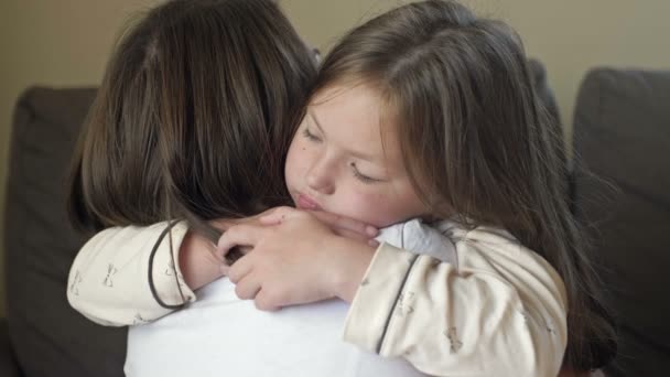 Проснувшись, маленькая девочка в пижаме с радостью обнимает свою мать. — стоковое видео