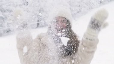 Genç ve güzel bir kadın dönüyor ve biri üzerine kar yağdırıyor. Kış eğlencesi.