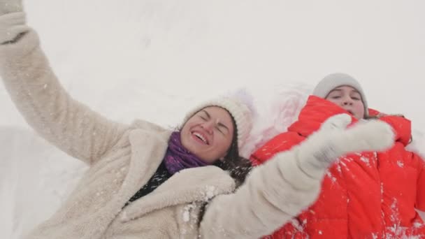 Young woman and teenager girl lie on the snow. They rejoice in the snow. Winter vacation. — Stock Video