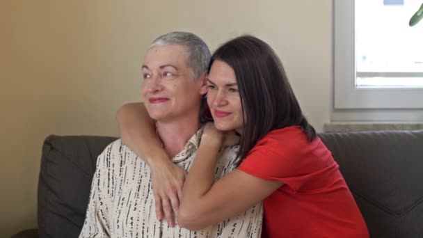 Eine erwachsene Tochter umarmt ihre Mutter. Eine ältere Frau hat nach einer Chemotherapie ein Nachwachsen der Haare. Liebe, Fürsorge und Unterstützung in der Familie eines Krebspatienten. — Stockvideo