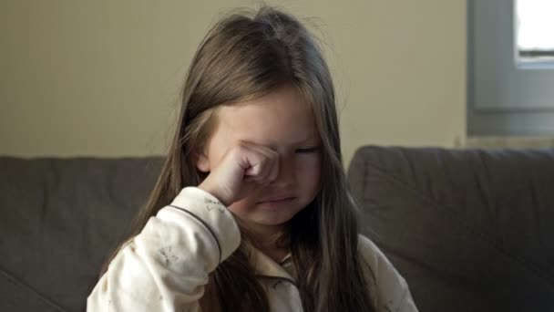 Uma menina de 6-7 anos que acaba de acordar esfrega os olhos. — Vídeo de Stock
