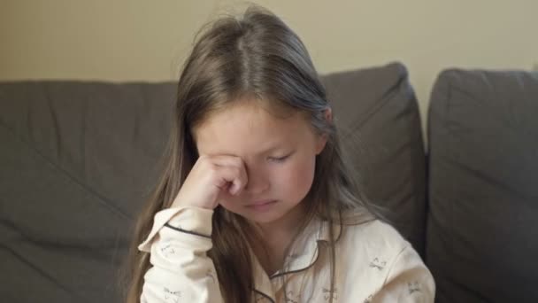 Портрет девушки в пижаме 6-7 лет, которая только что проснулась. Ребенок потирает сонные глаза.. — стоковое видео