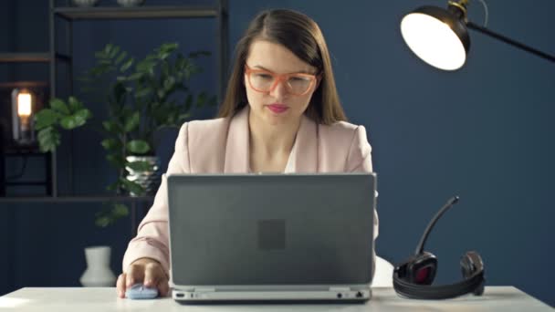 Ritratto di una giovane donna con un auricolare che lavora in un computer portatile. Operatore di call center educato. Donna d'affari comunica con un sorriso con i partner commerciali. — Video Stock
