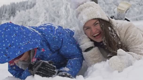 Dvě mladé ženy leží ve sněhu a smějí se. Zimní zábava.