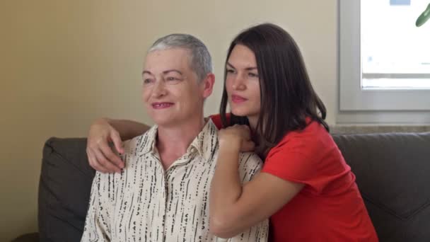 Una hija adulta abraza a su madre. Una mujer mayor tiene el crecimiento del cabello después de la quimioterapia. Amor, cuidado y apoyo en la familia de un paciente de cáncer. — Vídeo de stock