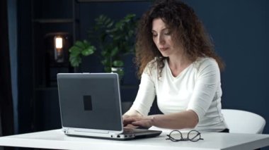Laptopta konsantre olarak çalışan güzel bir kadının portresi. Kadın yaptığı işin sonucundan memnun..