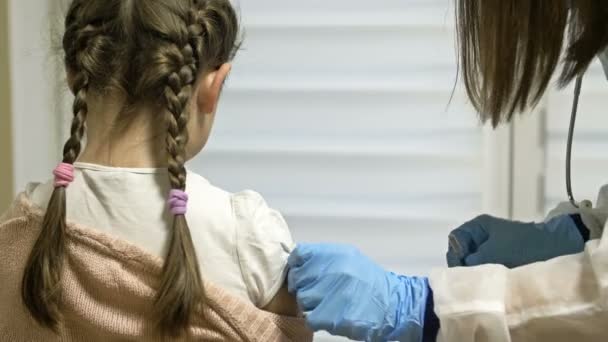 Дівчині шкільного віку дають вакцину. Обов'язкова вакцинація. Дитині дають вакцинацію в плечі в клініці . — стокове відео